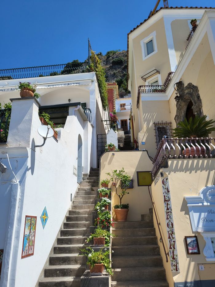 Mastering the First Impression: Your intriguing post title goes here A picturesque staircase leading through Mediterranean buildings, basking in daylight.